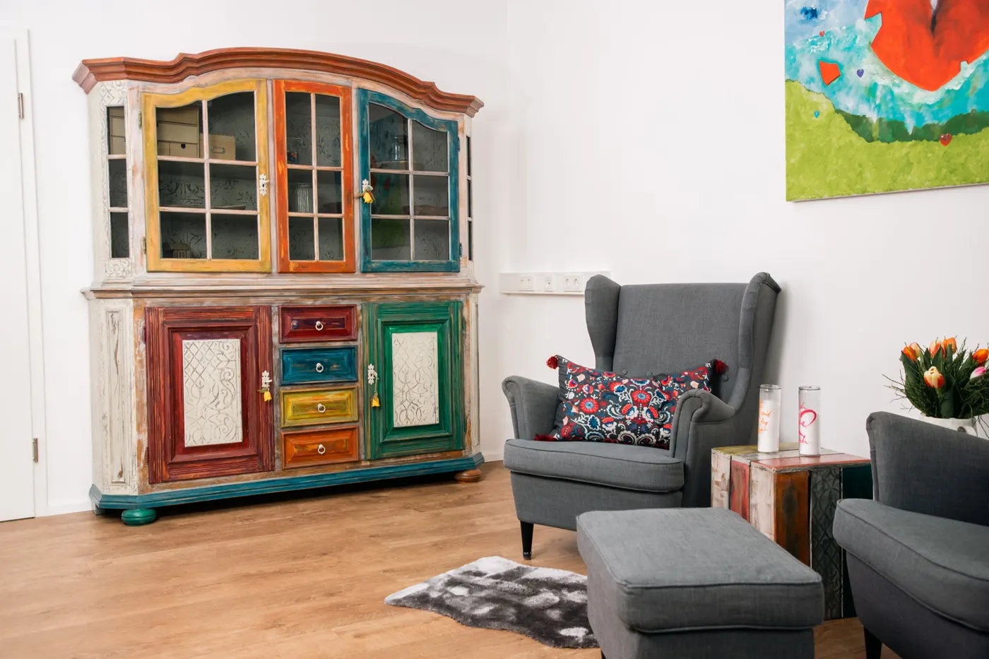 Wartebereich mit buntem Buffetschrank und grauen Sesseln